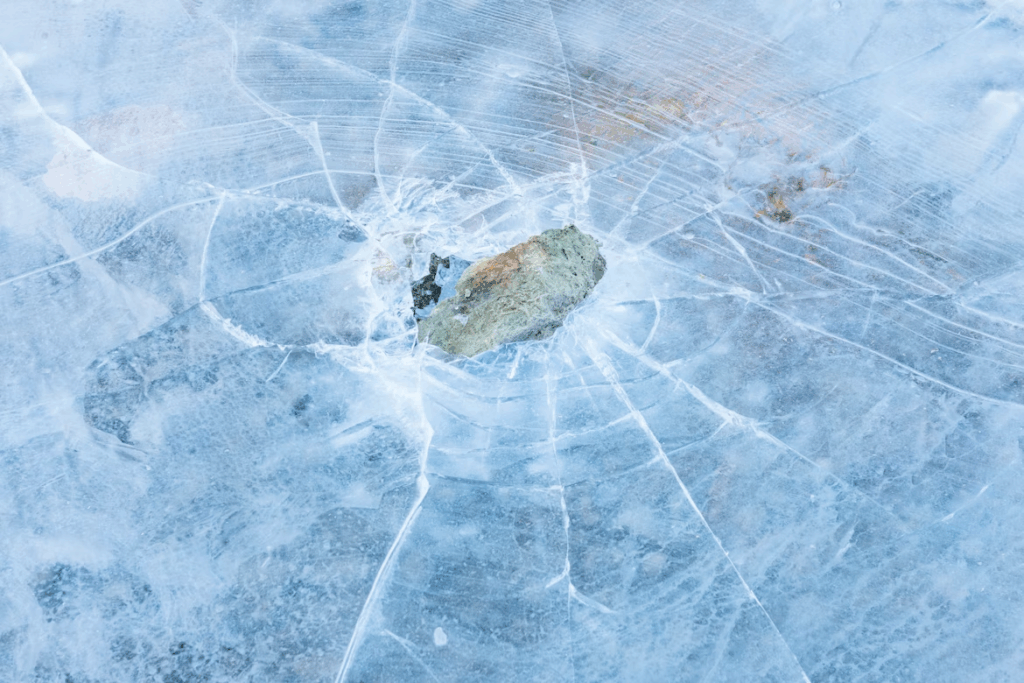 Close-up of a rock embedded in cracked blue ice, a literal “break the ice” concept