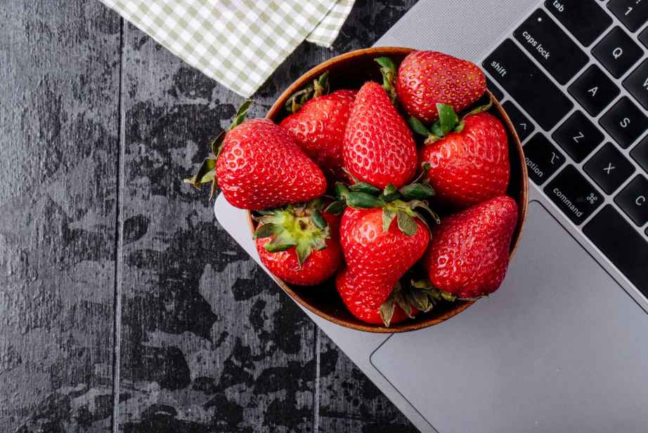 Bowl of fresh strawberries on a laptop, illustrating the “internet weighs less than a strawberry” comparison.