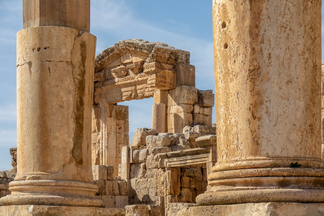 Ancient Roman ruins with weathered stone columns framing a carved arch and masonry blocks